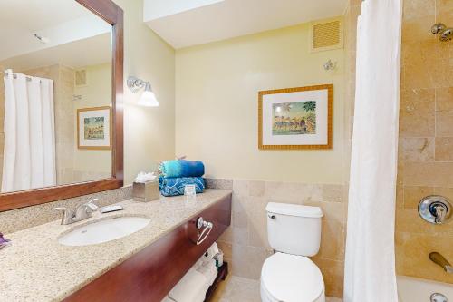 a bathroom with a sink and a toilet and a mirror at Kauai Beach Resort #1317 in Lihue