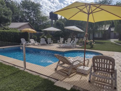 - une piscine avec 2 chaises et un parasol à côté dans l'établissement Cabañas Midelem, à Chascomús
