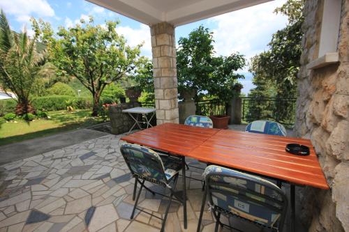un patio con tavolo e sedie in legno di Apartments and rooms by the sea Medveja, Opatija - 2305 a Lovran (Laurana)