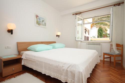 a white bedroom with a bed and a window at Apartments by the sea Mali Losinj (Losinj) - 2485 in Mali Lošinj