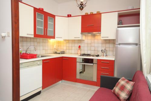 a kitchen with red cabinets and white appliances at Apartments by the sea Mali Losinj (Losinj) - 2485 in Mali Lošinj