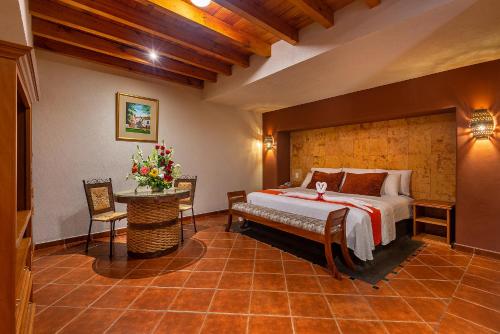 Hotel la Parroquia في باتزكوارو: غرفة نوم بسرير وطاولة مع ورد