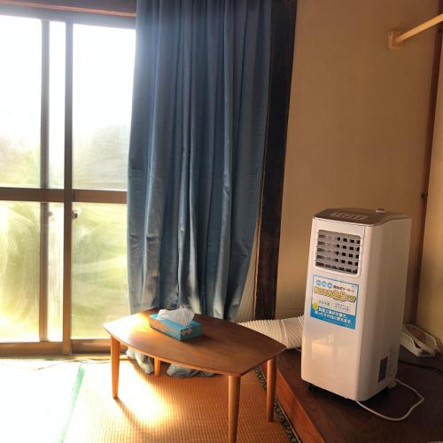 a room with a table and a refrigerator and a window at Astuto Riders House in Annaka