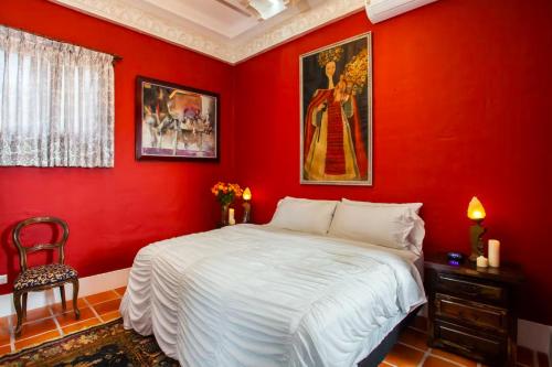 a red bedroom with a bed and a chair at Garlands Del Rio in Puerto Vallarta