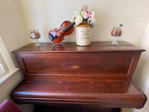 a wooden dresser with a violin and flowers on it at Room in family home near Penny Lane Liverpool in Liverpool