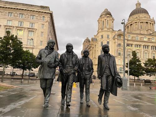 a statue of the beatles in front of a building at Room in family home near Penny Lane Liverpool in Liverpool