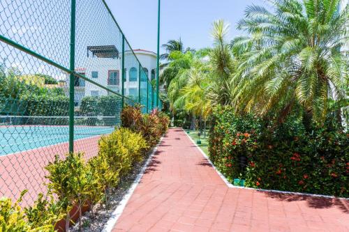 a tennis court with palm trees and a fence at Paseo del Sol Condohotel by BVR in Playa del Carmen