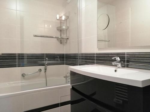 een witte badkamer met een wastafel en een bad bij Beautiful apartment by the harbor in Port-en-Bessin-Huppain in Port-en-Bessin-Huppain