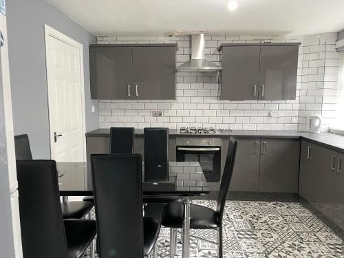 a kitchen with a black table and black chairs at Cozy Nights - Shawholm Cr in Mansewood