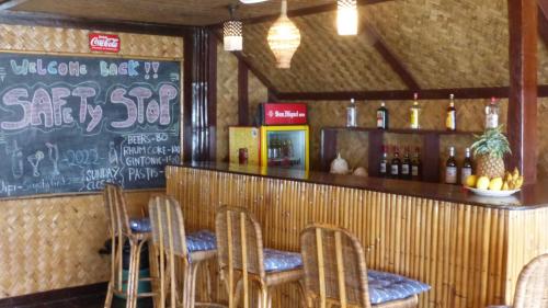 ein Restaurant mit einer Bar mit Stühlen und einer Tafel in der Unterkunft Bangka Hostels in El Nido