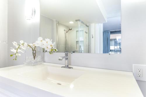 Un baño blanco con lavabo y espejo. en Kona Mansions 123, en Kailua-Kona