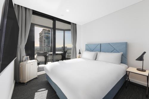 a hotel room with a large white bed and a window at Meriton Suites Surfers Paradise in Gold Coast