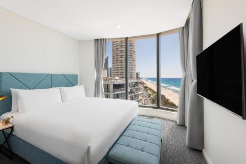 a hotel room with a bed and a view of the ocean at Meriton Suites Surfers Paradise in Gold Coast