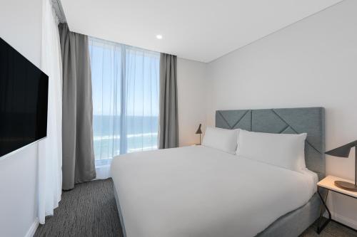 a hotel room with a bed and a large window at Meriton Suites Surfers Paradise in Gold Coast
