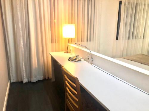 um quarto com uma secretária com um candeeiro e uma cama em Apto Privativo em Hotel de Luxo no Ibirapuera em São Paulo