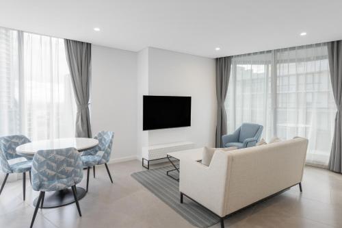 a living room with a couch and a table and chairs at Meriton Suites Surfers Paradise in Gold Coast