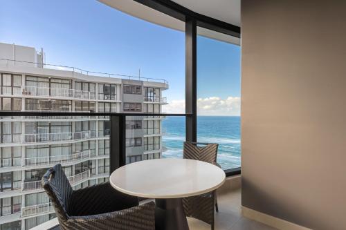 a table and chairs in a room with a view of the ocean at Meriton Suites Surfers Paradise in Gold Coast