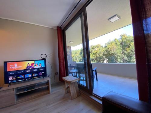 a living room with a television and a large window at Depto al lado de la Playa en el Centro de Pucón in Pucón