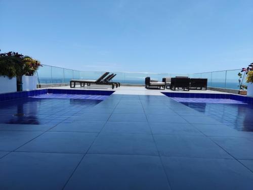 a swimming pool with chairs and a view of the ocean at Departamento Suite frente al mar Poseidon Manta in Manta