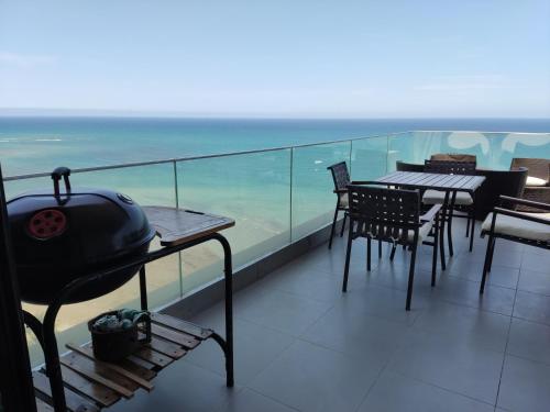 a balcony with tables and chairs and a grill at Departamento Suite frente al mar Poseidon Manta in Manta