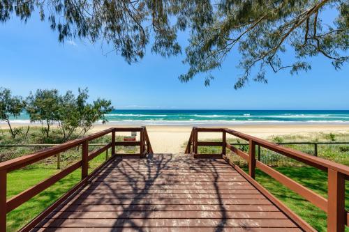 a wooden bridge leading to a beach with the ocean at Meriton Suites Surfers Paradise in Gold Coast