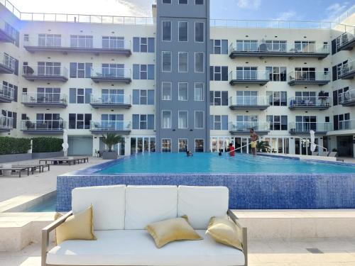 a white couch in front of a large swimming pool at ARUBA DREAM GETAWAY 2BR/2BT OCEAN & POOL VIEW in Oranjestad