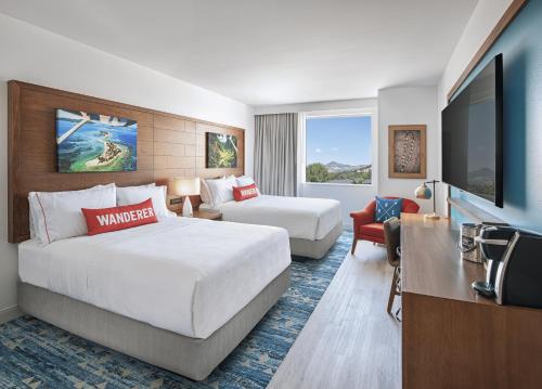 a hotel room with two beds and a flat screen tv at Compass by Margaritaville Medford in Medford