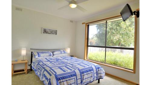 a bedroom with a bed and a large window at Family Retreat on Anderson in Inverloch