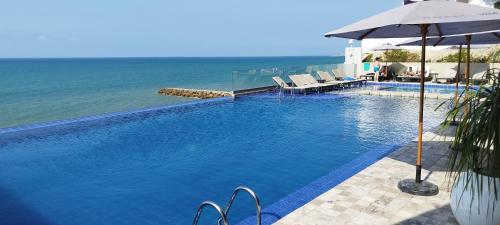 una piscina con sombrilla y el océano en Departamento Suite frente al mar Poseidon Manta en Manta