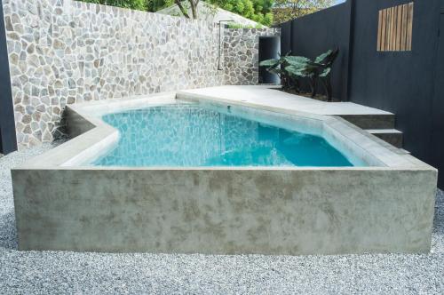 una piscina con una pared de piedra y escaleras en Pobla Hotel, en Oslob