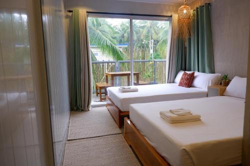 ein Hotelzimmer mit 2 Betten und einem Fenster in der Unterkunft Lubihan Siargao in General Luna