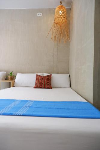 a bedroom with a white bed with blue sheets and a chandelier at Lubihan Siargao in General Luna