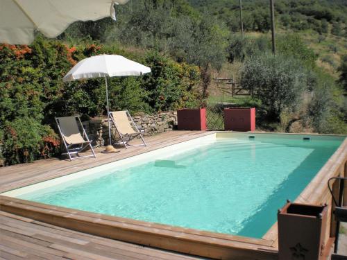 a large swimming pool with an umbrella and two chairs and an umbrella at Belvilla by OYO Mulino in Cortona