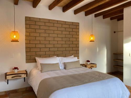 ein Schlafzimmer mit einem großen weißen Bett mit zwei Leuchten in der Unterkunft Hotel Alandalus in Villa de Leyva