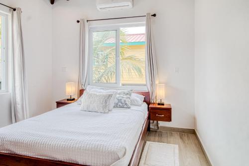 a white bedroom with a bed and a window at Tres Palmas Beach House in Maya Beach