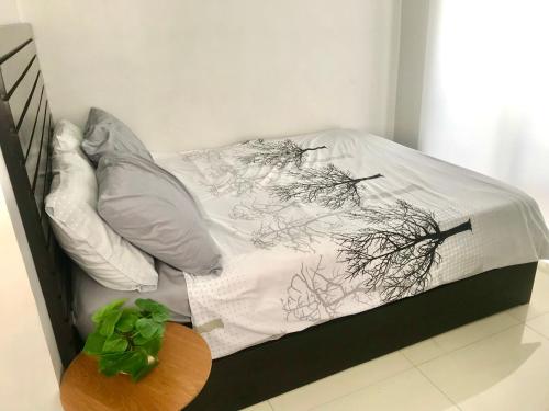 a bed with a black and white comforter and a table at Cozy and Full Service Condo at the Heart of Bacolod in Bacolod