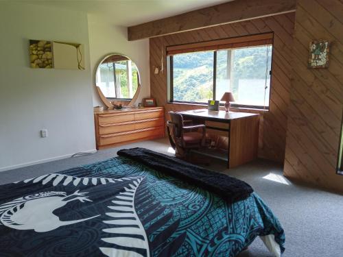 een slaapkamer met een bed en een bureau bij Waiotemarama Falls Lodge in Opononi