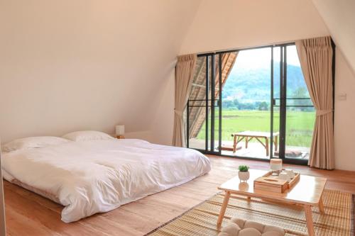 ein Schlafzimmer mit einem Bett, einem Tisch und einem großen Fenster in der Unterkunft Khao Kiang Na เขา เคียง นา in Ban Muang Kut