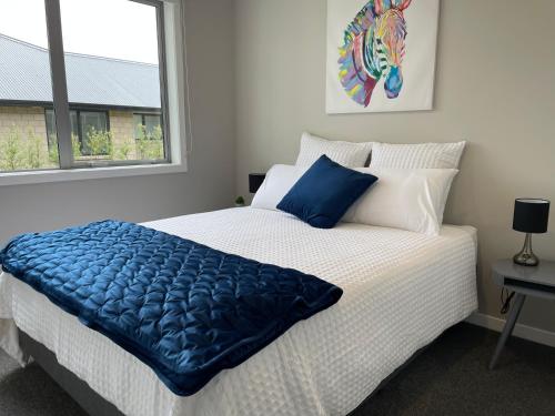 a bedroom with a bed with a blue blanket on it at Pauanui Lakes - Golf Resort in Pauanui