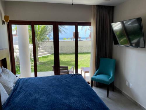 1 dormitorio con cama, silla azul y ventana en Casa Diany en Mahahual