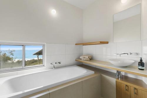 bagno con vasca, lavandino e finestra di Windform House a Moggs Creek