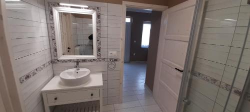 Baño blanco con lavabo y espejo en Rigó Apartman, en Keszthely