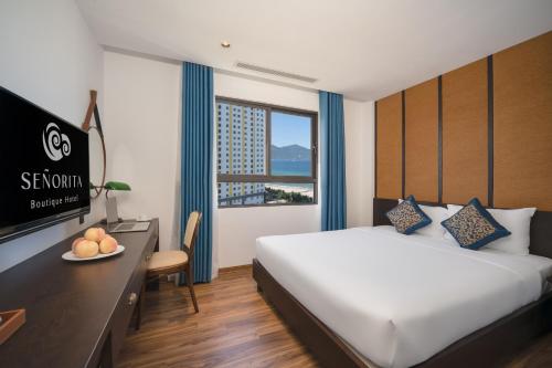a hotel room with a bed and a desk and a television at Se&ntilde;orita Boutique Hotel in Da Nang