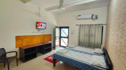 a bedroom with a bed and a desk and a tv at Iora Guest House in Bharatpur