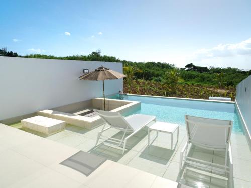 a patio with chairs and an umbrella and a swimming pool at ADANRESORT LANA Villa Suite in Motobu