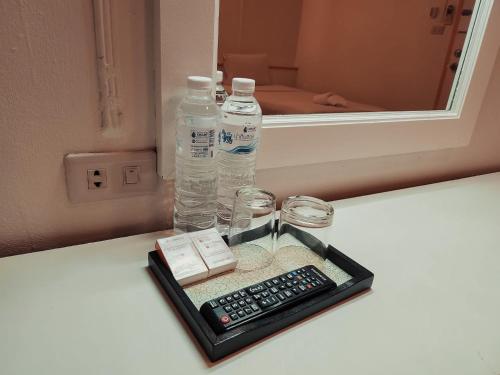 a tray with a remote control and a bottle of water at Asia Grand Hotel in Hat Yai