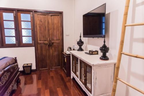 a room with a television and a desk with a bed at Ruanmata Homestay in Chiang Mai