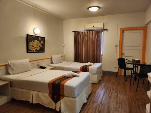 Habitación de hotel con 2 camas y mesa en Asia Grand Hotel, en Hat Yai