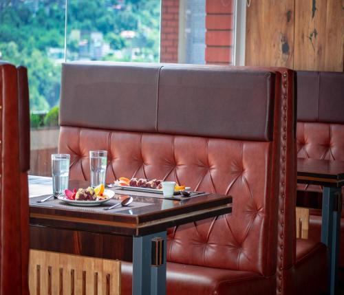 a table with two plates of food on a leather couch at Oro Montana Hotels and Resort in Bhurtuk