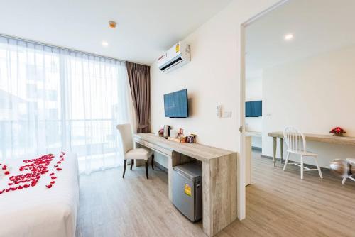 a hotel room with a bed and a desk and a table at LullaBella Hotel Patong in Patong Beach